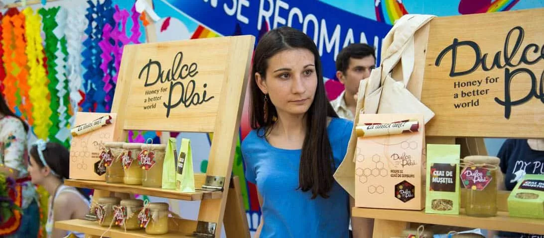 Liza at work at Dulce Plai Young woman with long dark hair standing next to honey products