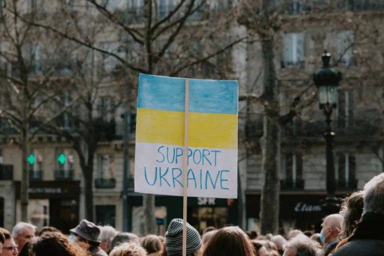 A crowd of people with someone holding up a sign 'Support Ukraine'