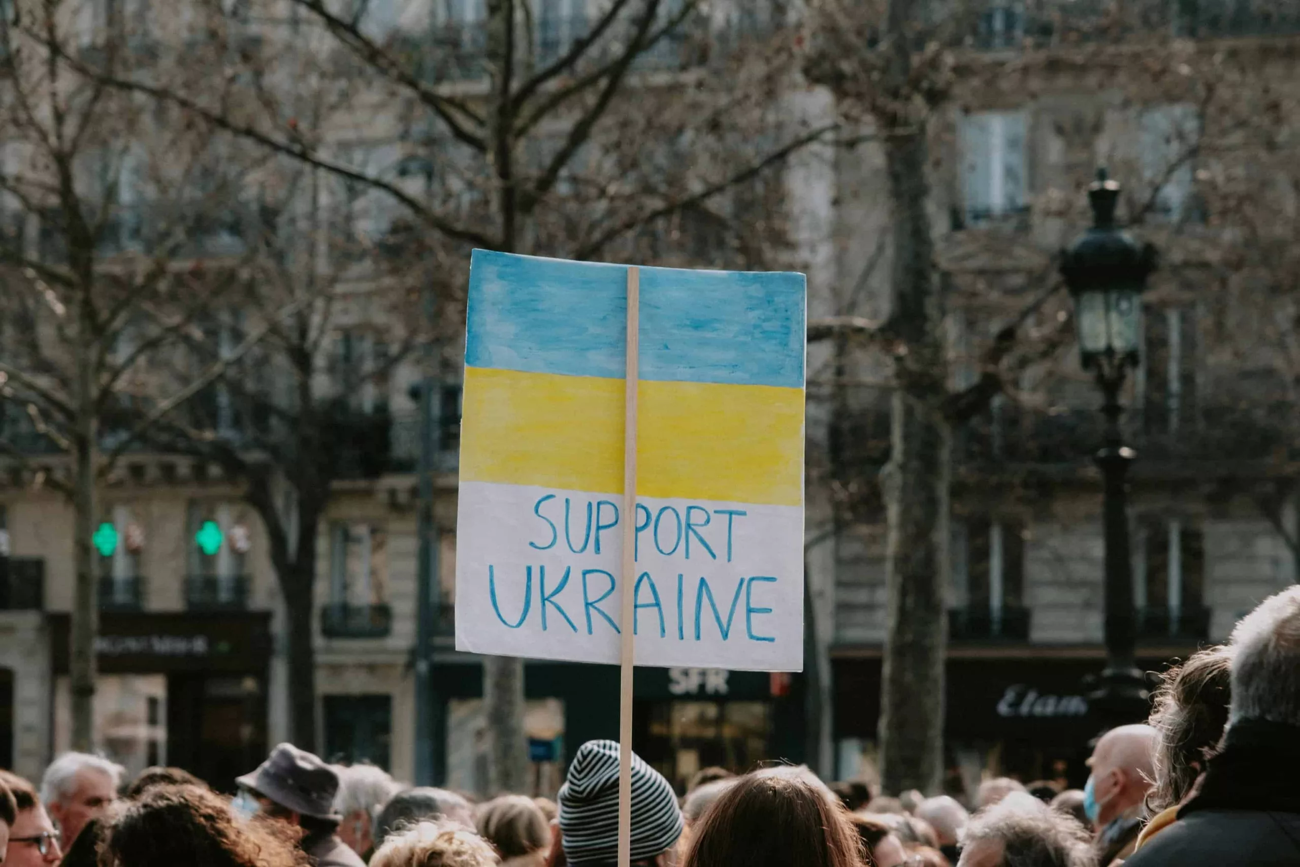 pexels-mathias-reding-11421332 A crowd of people with someone holding up a sign 'Support Ukraine'