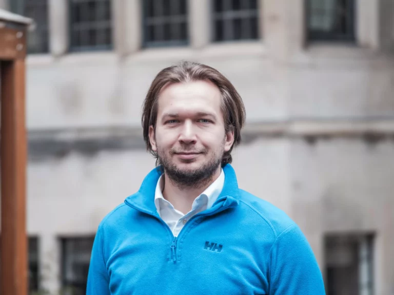 Man with long hair standing in front of building