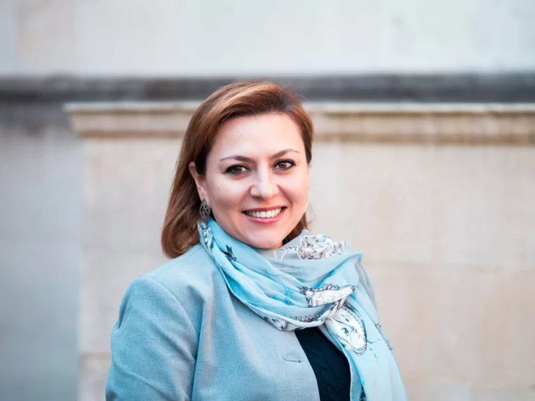 Woman smiling wearing a blue suit and scarf