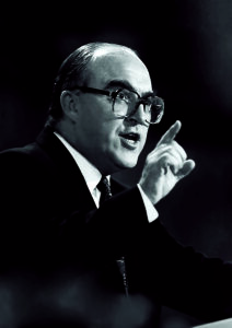 John Smith pointing his finger as he gives a speech
