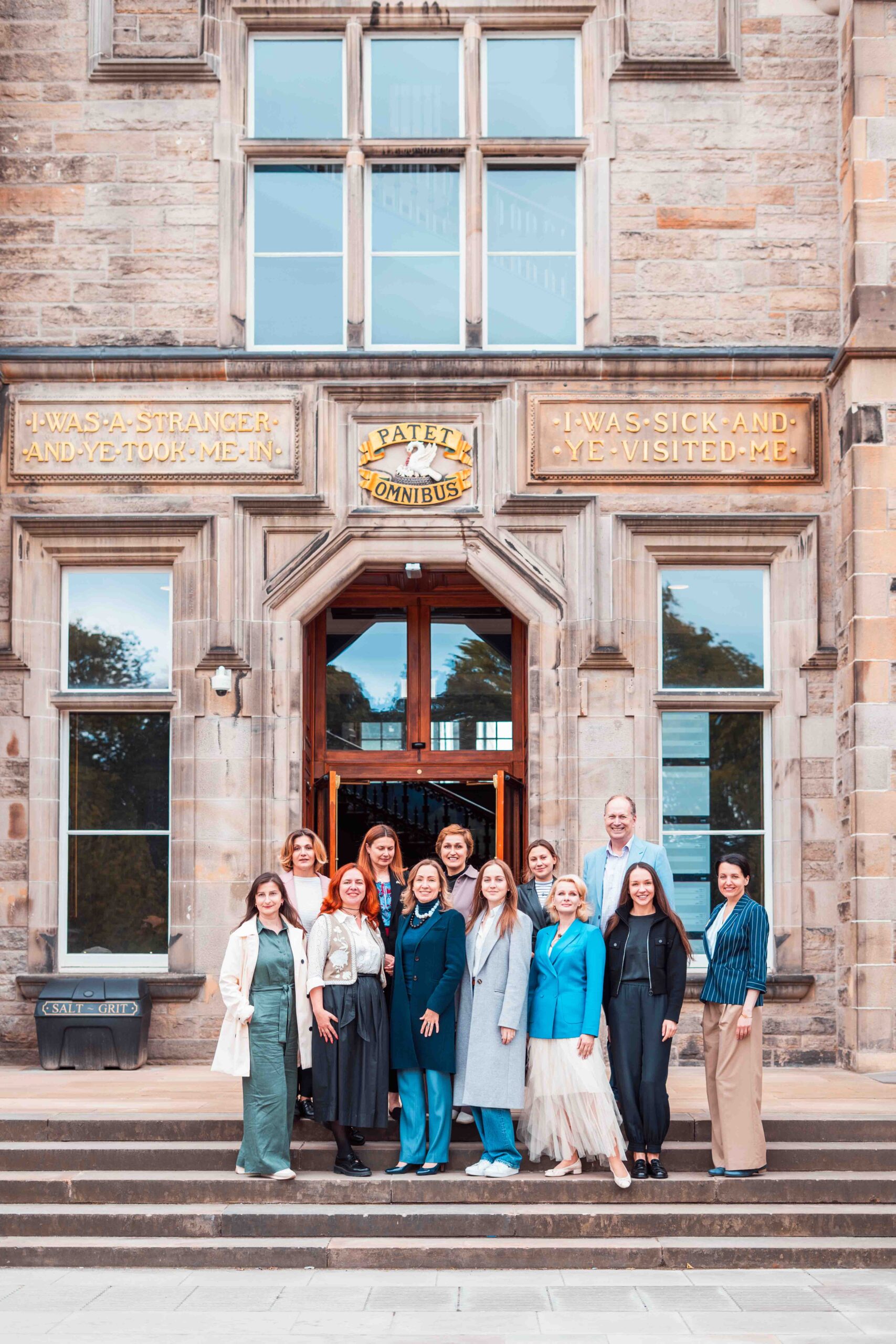 A group of women standing on the steps of Edinburgh University in front of a grand door