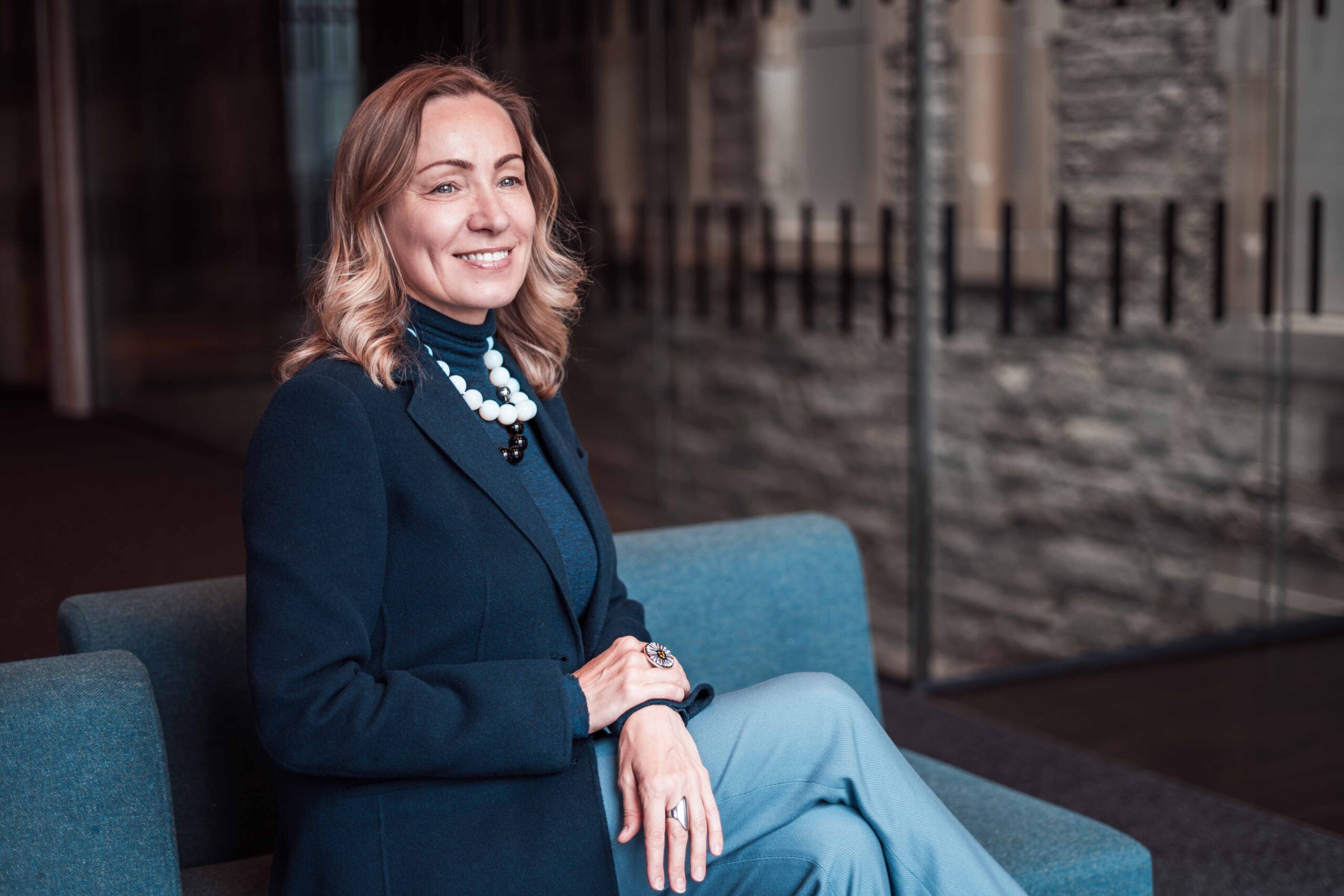 Ukrainian Women's Leadership Programme Woman in trousers and blazer sitting cross legged on sofa