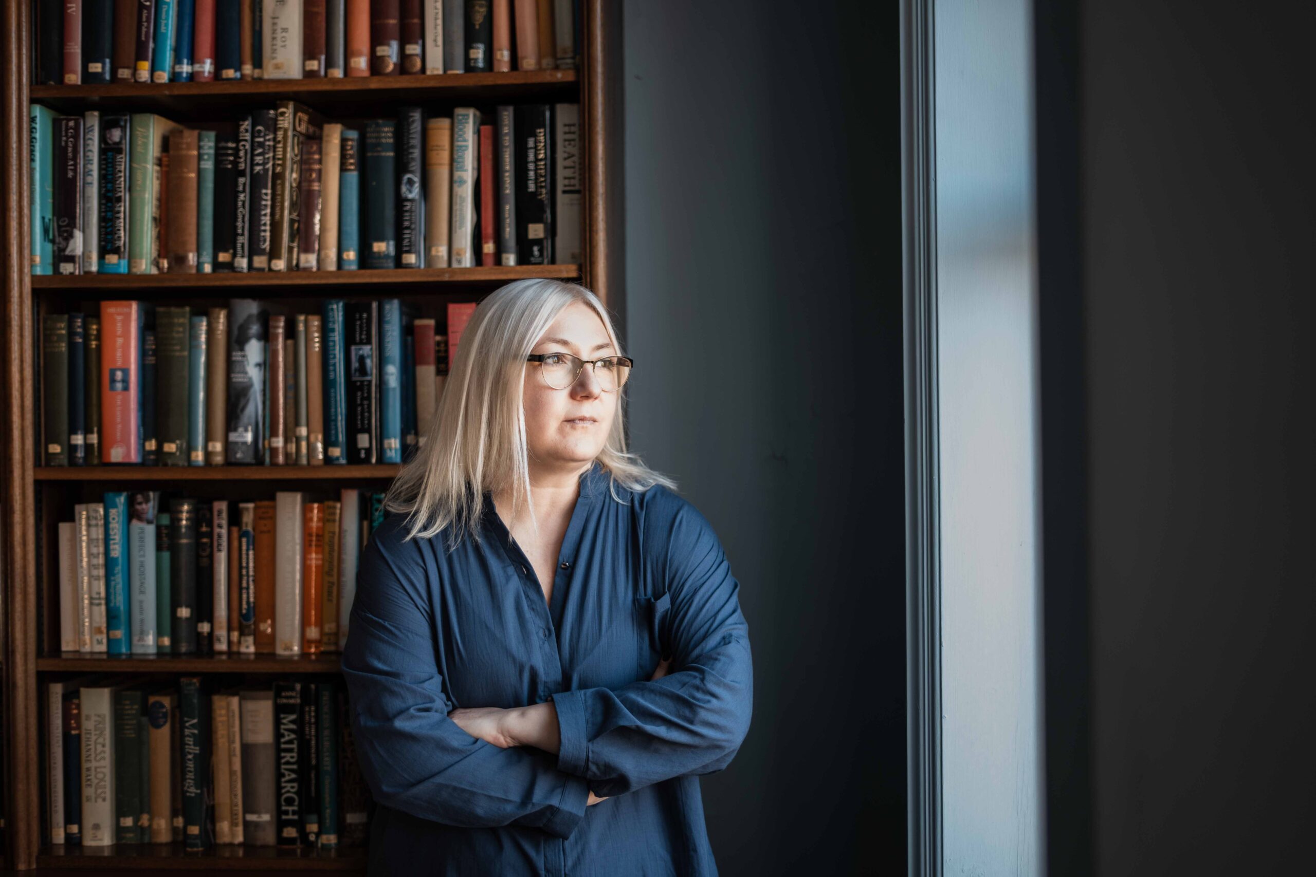 A female Fellow in a library looking out the window