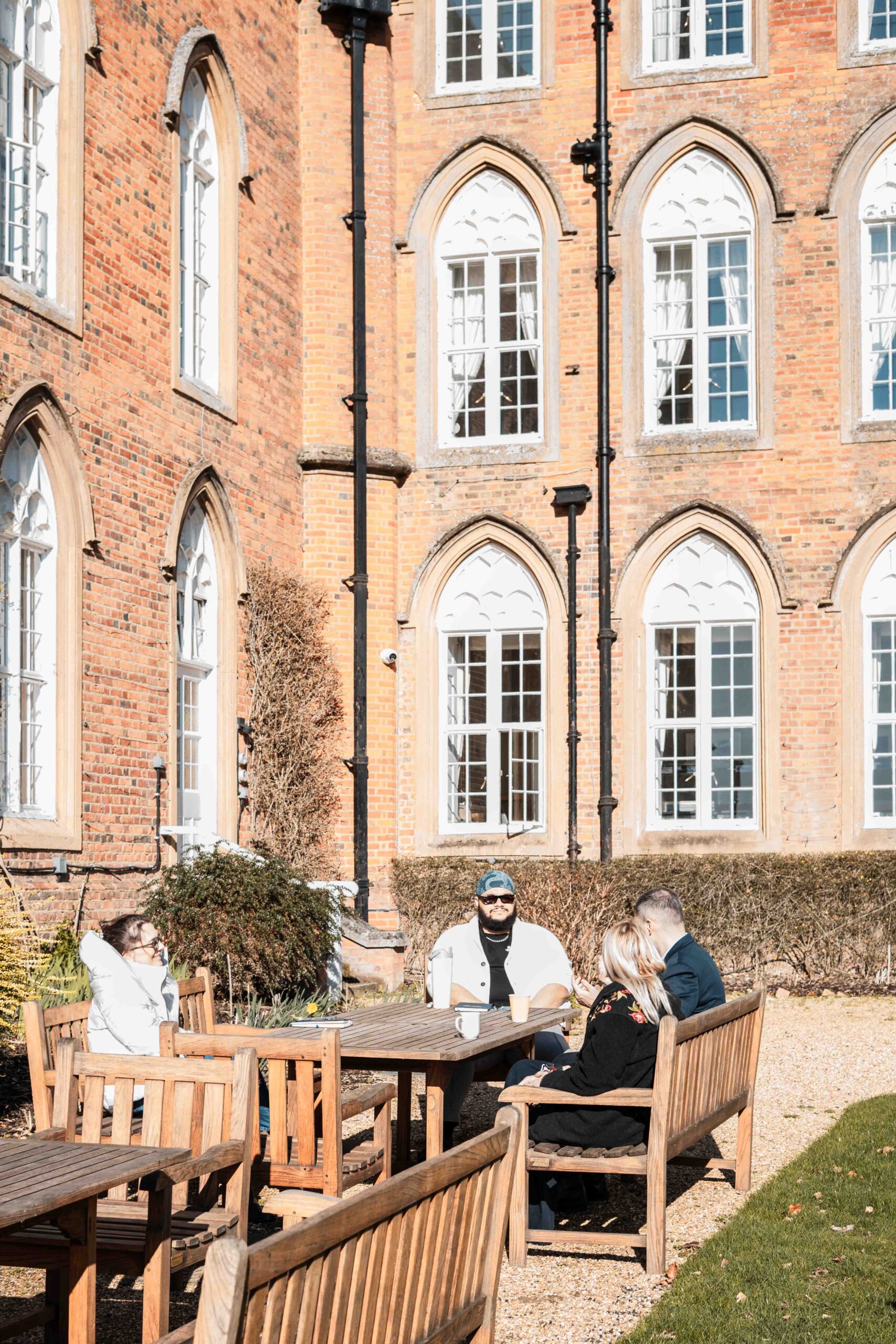 Fellows talking at a table outside Cumberland Lodge Fellows talking at a table outside a grand building