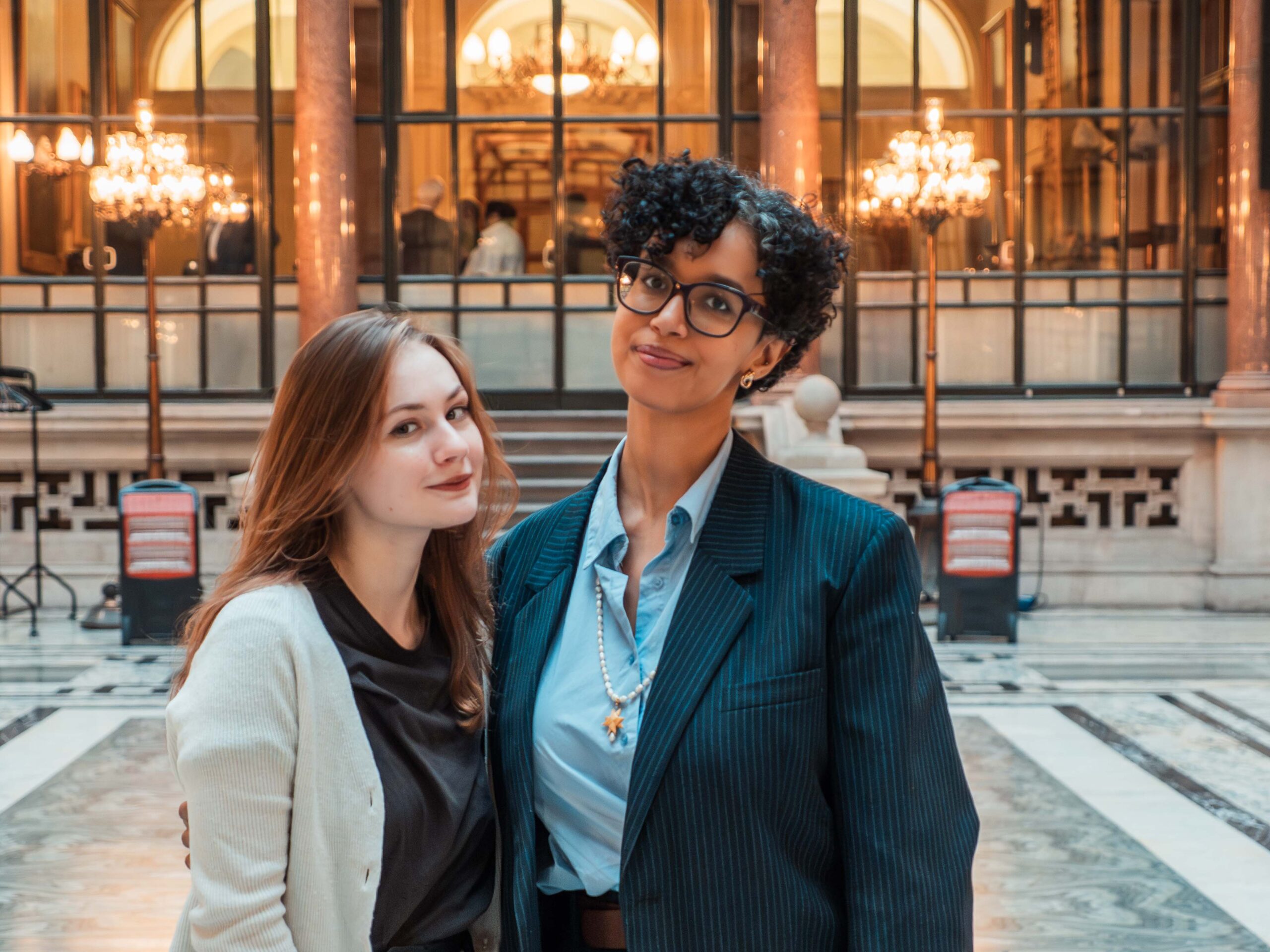 Fellows at FCDO Two Female Fellows standing in a large grand room with lots of lights