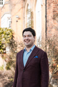 Man in a suit in front of grand house